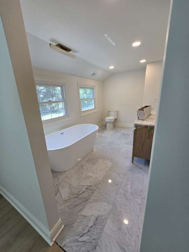 Bathroom renovation in progress with a freestanding tub, marble-look flooring, and a protected vanity.