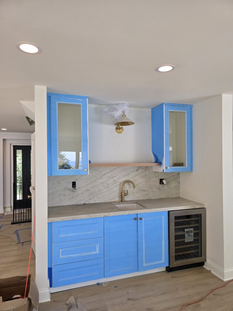 Custom home bar installation with stone backsplash, quartz countertop and built-in beverage cooler