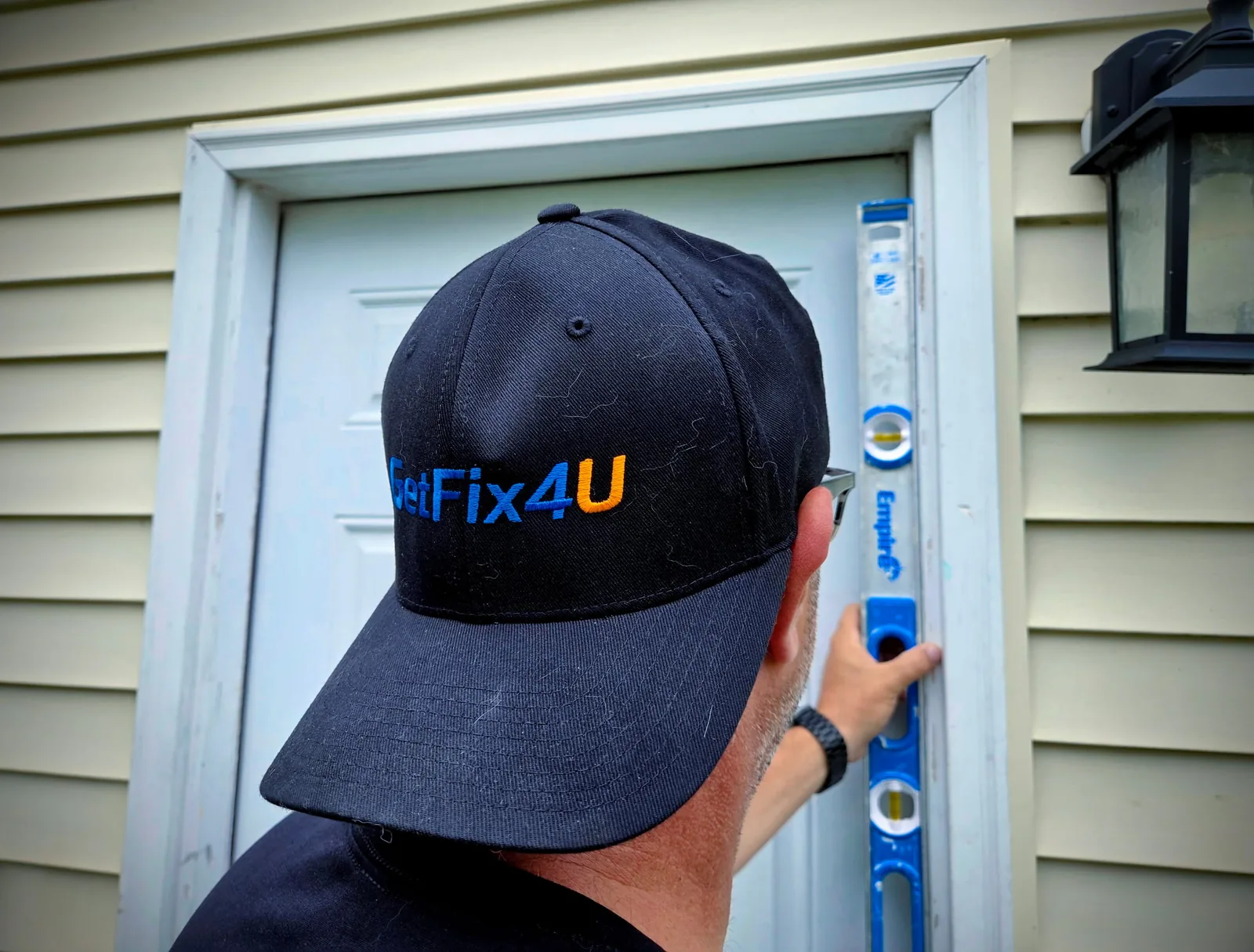 Technician checking a door frame with a level near the front entrance.