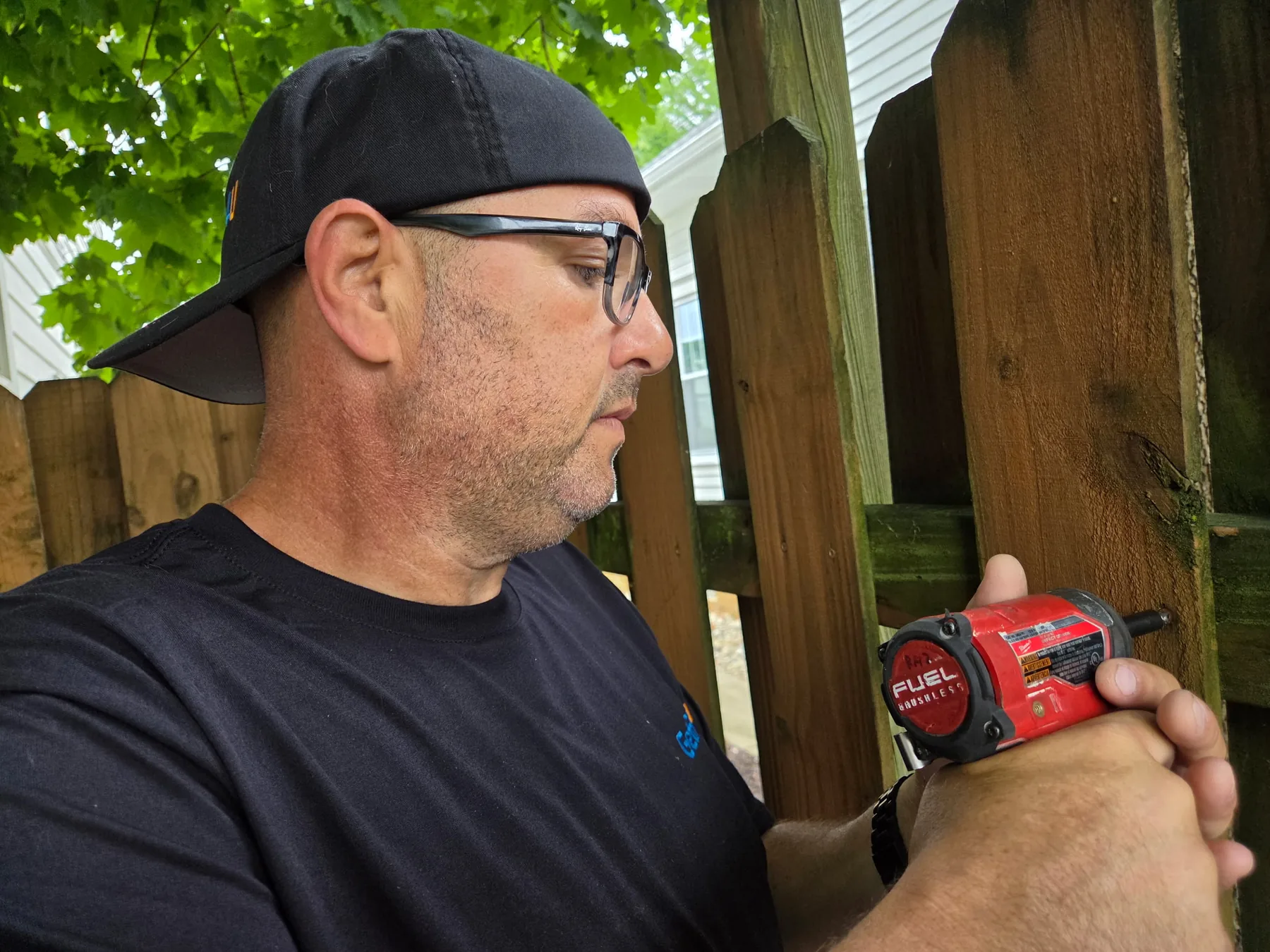 Technician using a cordless impact driver to repair a wood fence.