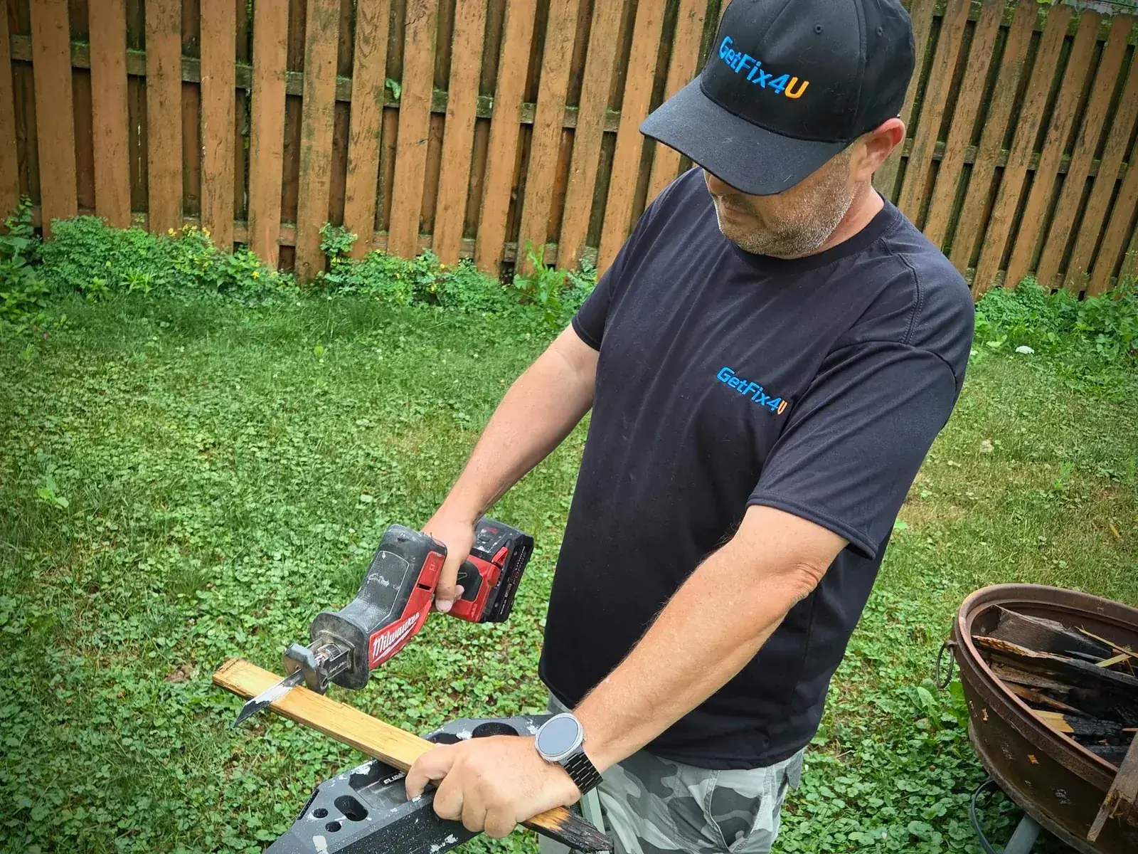 Technician measuring and cutting a wood board outdoors with a cordless tool.