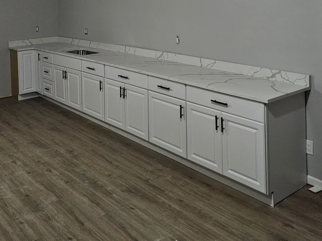 Finished white cabinet run with a marble-look quartz countertop and undermount sink.