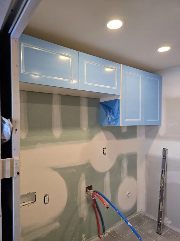 Finished laundry room with upper cabinets, under-cabinet lighting, and tile flooring.