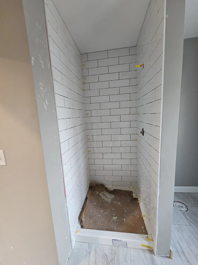 Finished white subway-tile shower niche with a matching marble-look tile floor.