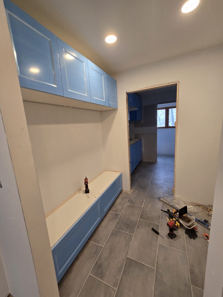 Custom mudroom storage installation with built-in cabinets, hanging space and quartz countertop